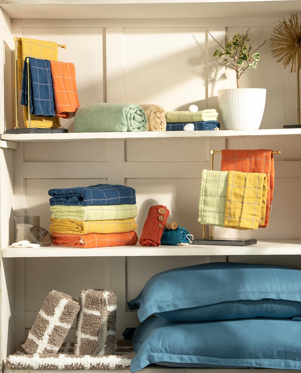 Colorful towels and bedding displayed on shelves with a neutral background
