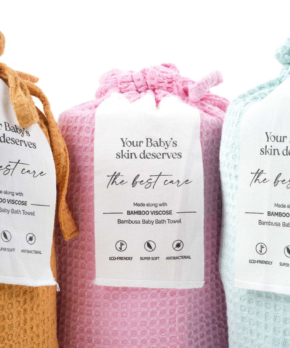 Three bamboo baby towels in different colors with labels on a white background.