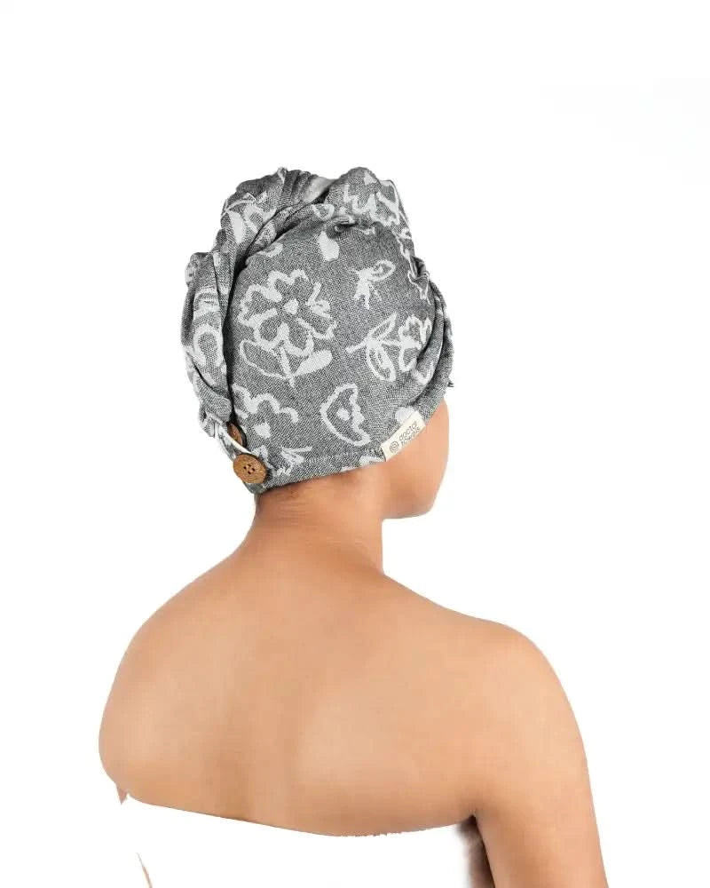 Person wearing a grey floral-patterned hair towel on a white background