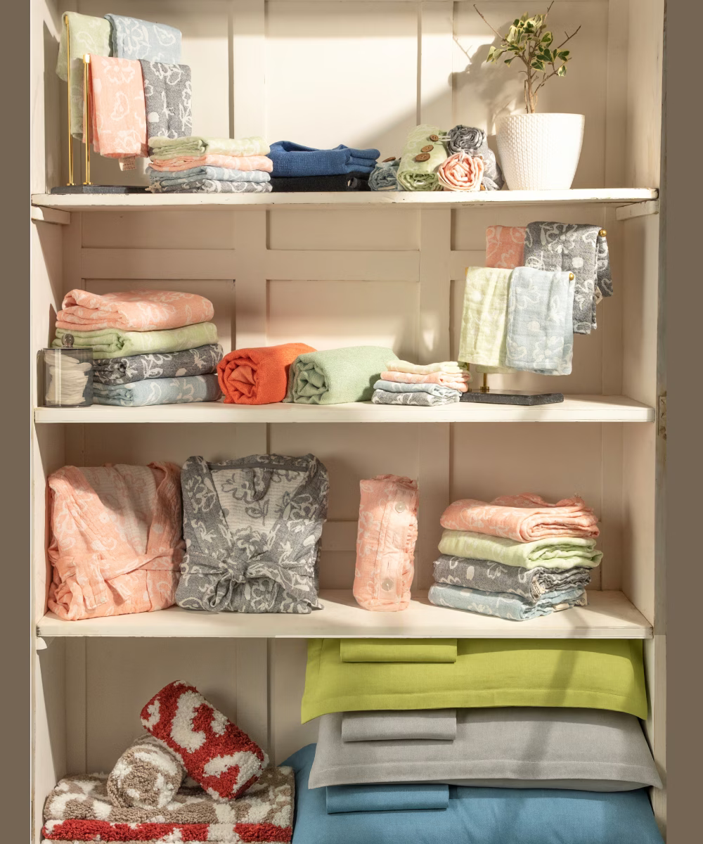 Shelves with folded clothes in various colors against a wooden panel background