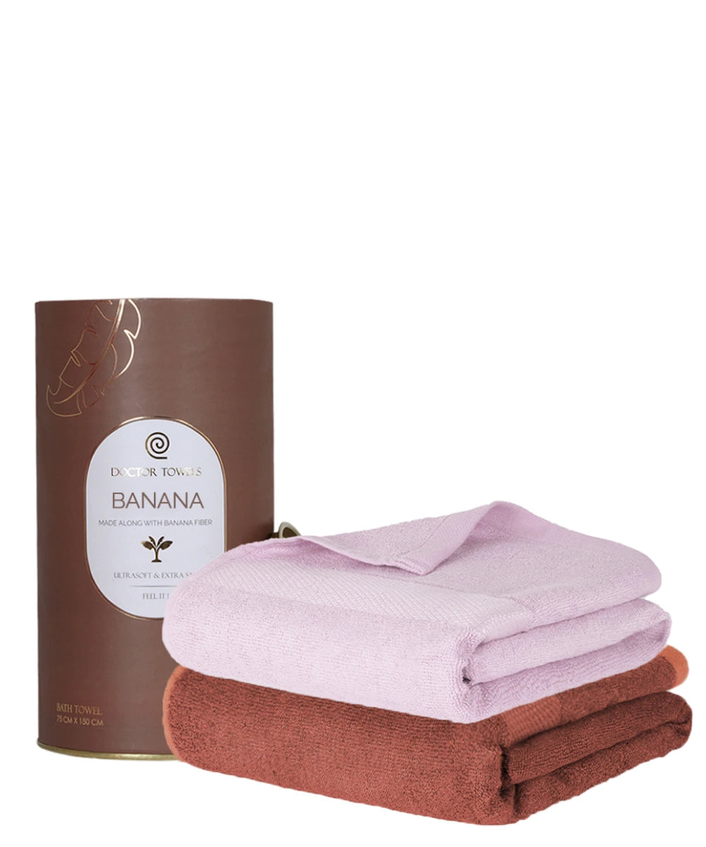 Folded pink and brown towels with a canister labeled 'Banana' on a white background