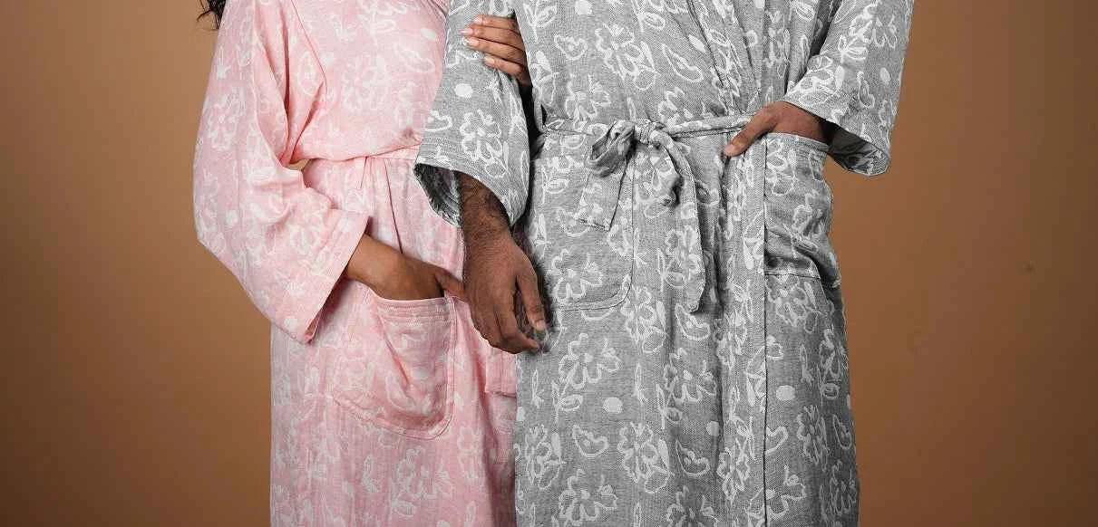 Two people wearing patterned robes against a beige background