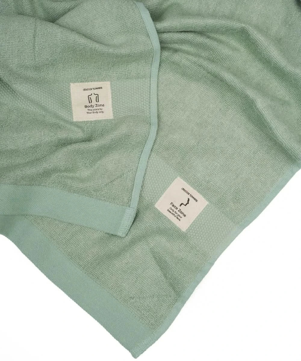 Sage green towel with brand label on a white background