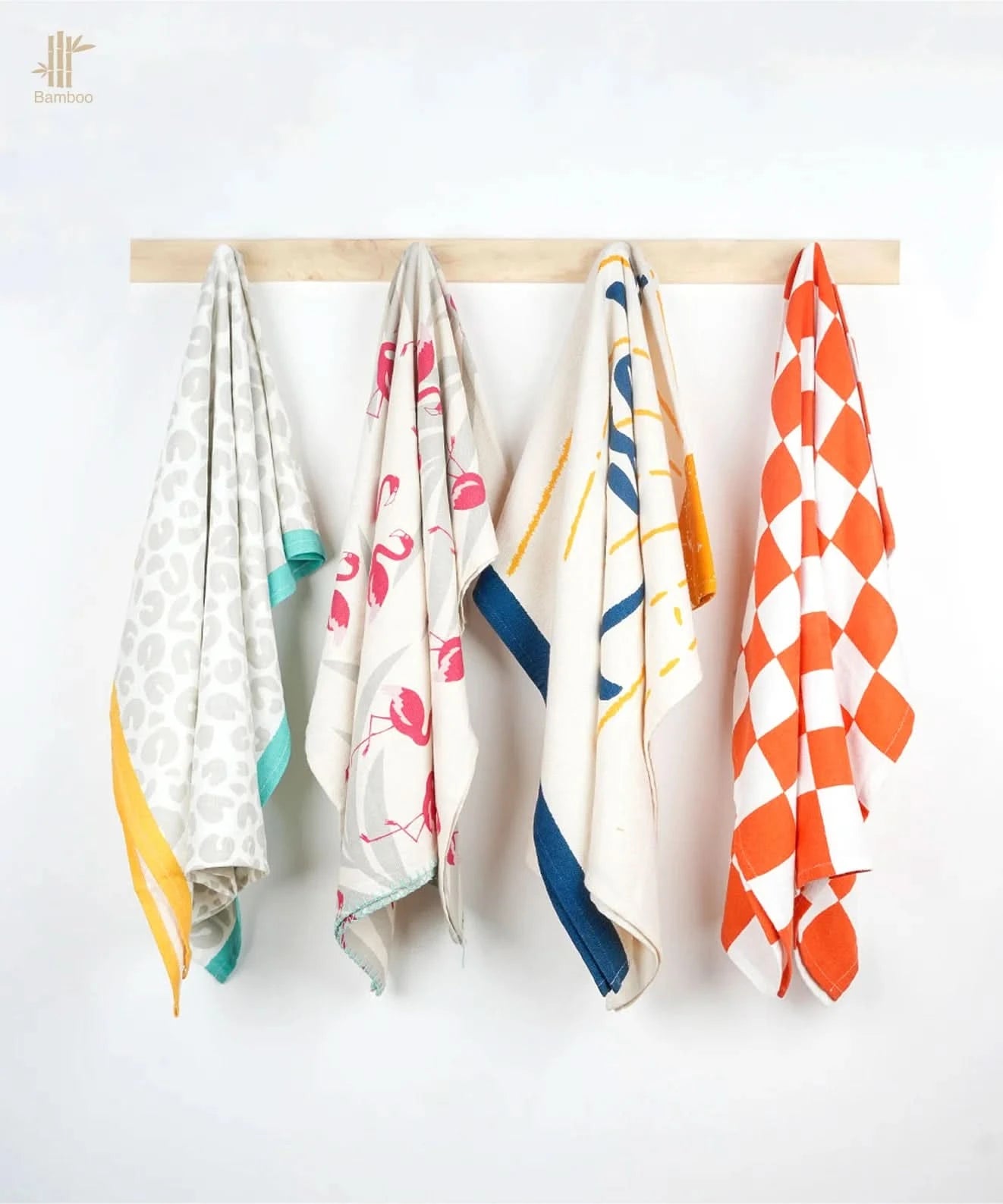 Four thirsty towels hanging on a wooden rod against a white background
